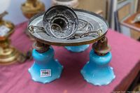 View of chandelier upside down showing brass ceiling mount piece before installation, three arms, and blue and white tulip-shaped glass shades.