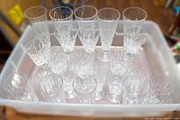 Overview of all crystal stemware and tumblers in clear plastic bin showing variety of sizes and styles.