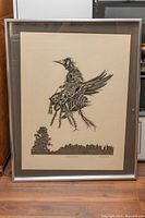 Framed black and white print of a knight-like figure with a bird and forest silhouette.