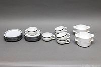 Full set showing grouped dessert plates, cups, saucers, and four white double-handle soup bowls.