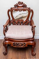 Front view of carved rosewood armchair with marble back insert and cushion