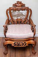 Full front view of carved rosewood armchair with marble back insert and seat cushion