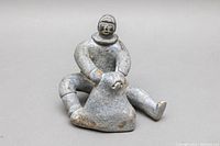 Front view of the soapstone carving showing seated Inuit figure holding an animal.