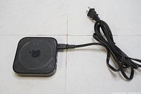 Top and bottom views of the Apple TV 4K device showing Apple logo and 'tv' logo, including attached power cord with US plug.