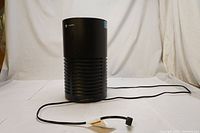 Full view of black cylindrical GermGuardian air purifier showing size and shape with power cord extended.