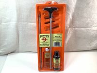 Image showing Hoppe's No. 9 rifle cleaning kit in sealed orange plastic packaging, including solvent, lubricating oil, cleaning rod, brush, adapters, and cotton patches.