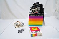 Polaroid Colorpack 80 camera displayed with its original box, instruction manual and a pack of Polaroid film on a white background.