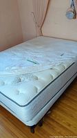 Full view of double bed with white mattress cover and visible mattress and box spring beneath