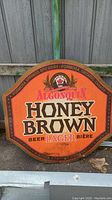 Full view of the octagonal metal beer sign with Algonquin Honey Brown Lager branding. Orange and brown honeycomb design with brass outline and brewery information.
