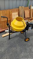 Side view of yellow mixing drum on black steel frame with wheels and handle