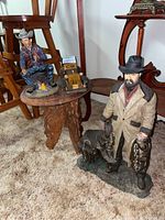 View of the overall lot including the large standing cowboy statue with dog, small Asian carved table holding the smaller cowboy figurine and carved wooden classic car