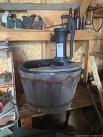 Cast iron hand pump mounted on wooden barrel in rustic setting