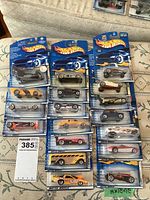 Top-down view of all 18 Hot Wheels cars arranged in three columns, showing packaging and vehicle variety