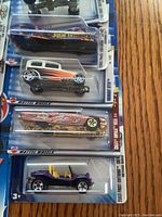 Close-up of five Hot Wheels cars in original blister packaging, showing different models and vibrant colors.
