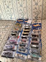 Photo showing 24 Hot Wheels cars in blister packs arranged on a surface, various styles and colors visible.