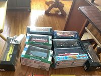 Group photo showing multiple unopened Cararama model cars and buses in original windowed boxes on floor.