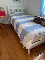 Full view of assembled white wooden single bed with bedding in room corner
