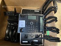 Top view of the 10 AudioCodes 440HD IP phones in a box, showing handsets and cords