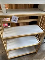 Wooden shoe rack with natural wood frame and three white shelves displayed in indoor environment.