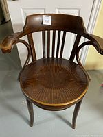 Front view of antique bentwood armchair showing wooden curved backrest, armrests and carved circular seat with etched radial pattern.