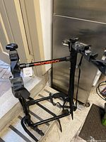 Front view of Norco bike rack showing padded arms and base supports for 3 bikes, black with orange logo.