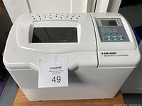 White Black & Decker All-in-One Plus bread maker with digital control panel and window on lid, placed on wooden surface