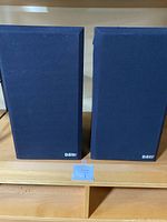 Two B&W DM110i bookshelf speakers with cloth grille covers, front view