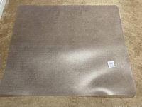 Clear carpet protector mat laid flat on carpet, showing texture and size relative to carpet