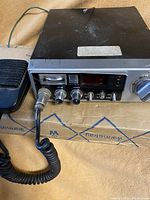 Full view of Fanon CB radio unit with microphone cable coiled in front, showing wear and dust on top casing.