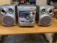 Front view of JVC stereo system with speakers on each side placed on a wooden table