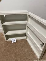 Open medicine cabinet showing interior with two shelves and mounting holes.