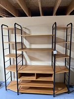 Full view of the shelving entertainment unit showing wood shelves and black metal frame structure with multiple levels of shelving.