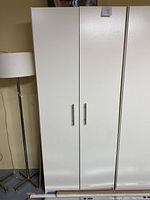 White pantry cabinet closed doors showing front view with two metal handles.