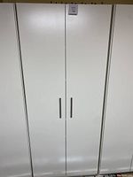 Closed view of white pantry cabinet showing doors with metal handles