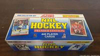 Rectangular box for 1990 Score NHL Hockey Premier Edition factory set containing 445 player cards, displayed on a brown textured surface.