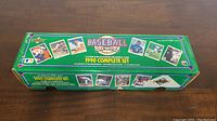 Photo of the green rectangular box labeled 'BASEBALL 1990 EDITION 1990 COMPLETE SET' by Upper Deck, featuring images of baseball cards and 3-D team logo holograms.