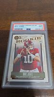 Front view of the 2021 Mac Jones rookie football card graded PSA 9, showing player action and label details.