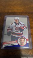 Photo of a 2023 Connor Bedard Regina Pats hockey card in a protective case, showing Bedard in action with Pats jersey.