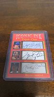 Photo of the Iconic Ink Triple Cuts card in protective plastic case showing Wayne Gretzky, Michael Jordan, and Mickey Mantle printed autographs and images.