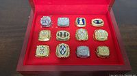 Top view of all 12 replica Super Bowl rings neatly arranged in a red velvet-lined display box.