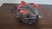 Side and top views of an electric circular saw labeled Skilsaw with 2.4 Hp 13 Amp specification, showing overall condition and details.