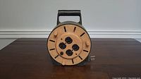 Front view of the extension cord reel showing the four outlets and winding pegs.