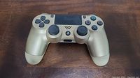 Top view of the gold PS4 DualShock controller showing buttons, analog sticks, and touchpad.
