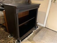 Photo showing the front and side view of the sturdy, dark finished two-shelf bookcase with carved trim and fluted columns on sides.