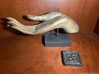 Side and front views of the metallic open hand sculpture mounted on a black base, shown with a square black incense holder featuring raised Om symbol.