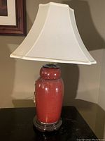 Pair of red porcelain table lamps with cream fabric shades and decorative branch details