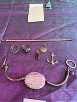 Photo of various sterling silver jewelry items including bracelets, rings, and pendants displayed on purple cloth.