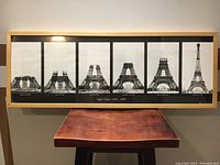 Framed photographic prints showing Eiffel Tower construction stages in six black-and-white photos with dates and annotations.