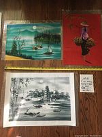 Three Asian original acrylic paintings on textile laying flat showing signatures, dimensions and varying colors: green landscape, red figure, black and white village.