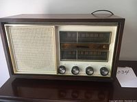 Front view of vintage Electrohome tube radio showing wooden casing, speaker grille, dual tuning windows, and control knobs.